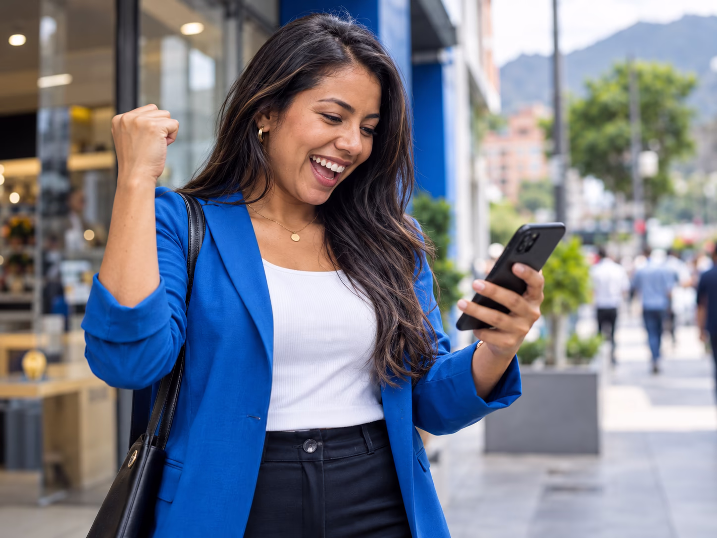 Vendedora celebrando en la calle mientras mira su celular